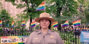 National park ranger standing in front of rainbow flags