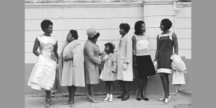 Black and white photograph of intergenerational Black women and girls standing and talking in front of a church.