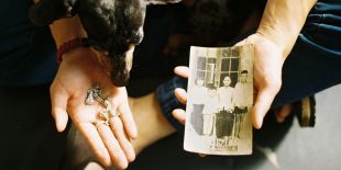man sitting with his dog holding fragments of material, paper