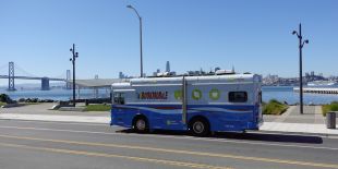 Bookmobile on a street in Treasure Island with the Bay Bridge, bay and City in the background.