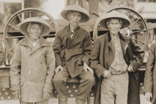 A sepia photo showing three elderly Chinese men wearing coats and woven hats.