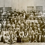 Sepia toned panoramic photograph of dozens of male workers lined up in 6 rows with a placard in the front that reads &quot;Legallet-Hellwig Tanning Co. April 18 - 1910&quot;