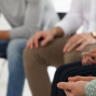 A group of people sitting in a circle seen from chest down with hands in their laps.